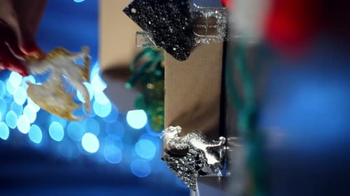 Hand Placing Ornament on Shelf with Festive Lights