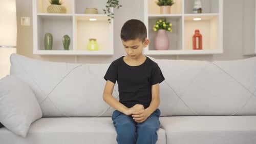 Young Boy Scratching Arm While Sitting on Sofa
