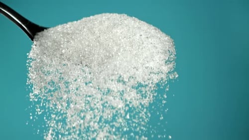 Sugar Pours Out of a Spoon on a Blue Background Filmed on a Highspeed Camera at 1000 Fps