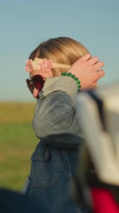 MiddleAged Woman Touches Hair with Flower Headband Resting By Motorbike Outdoors