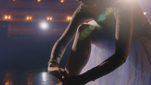 Graceful Ballerina Tying Pointe Shoes on Stage