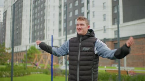 Cheerful Outdoor Scene Young Man Celebrates in Park Man in Warm Clothing Expresses Joy Outdoors