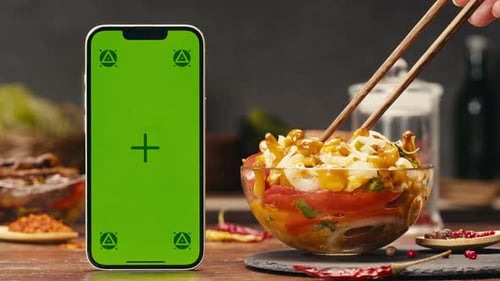 A Green Screen Mobile Phone a Portable Communications Device is on a Table Next to a Bowl of Canned