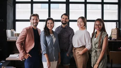 Young business team portrait standing in a modern office building looking at camera