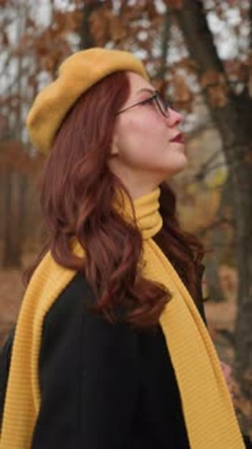 Woman with Yellow Muffler Looking Around in Windy Forest