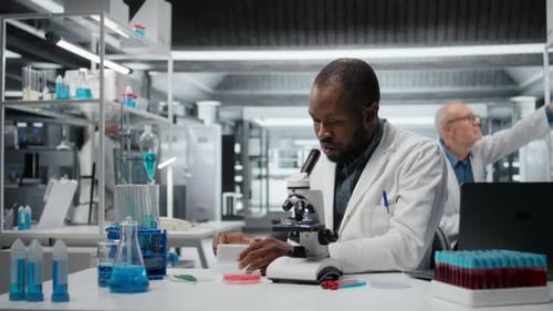 Scientist Examining Sample with Microscope in Modern Laboratory