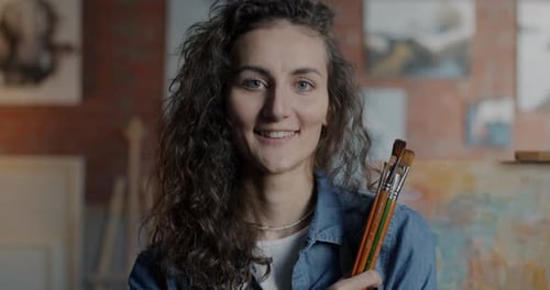Portrait of Attractive Young Woman Artist Looking at Camera with Creative Workshop in Background