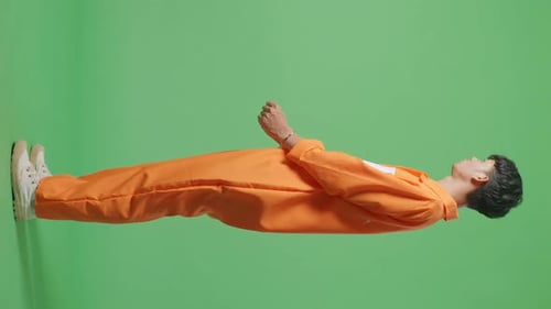 Vue latérale du corps entier d'un prisonnier asiatique menotté debout sur l'écran vert