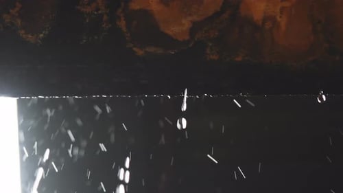 Intense close-up of rainwater dripping from the edge of a wall, creating a captivating visual displa