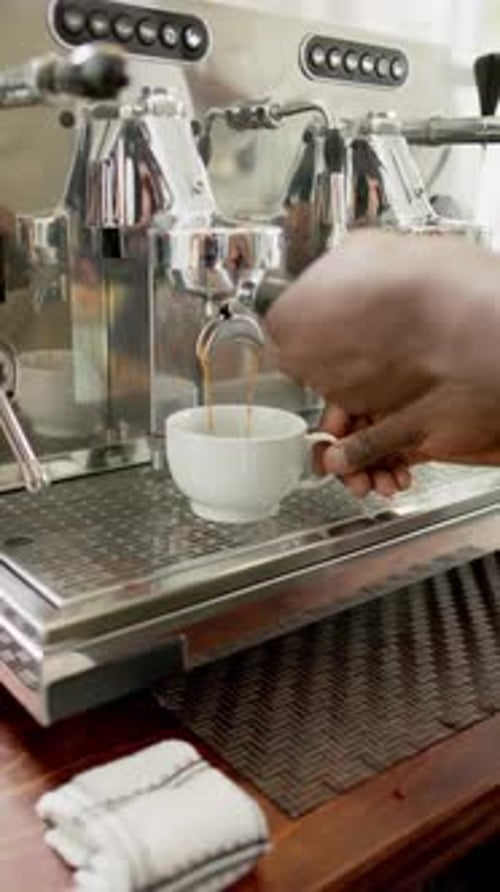 Vertical video: Making espresso, barista using coffee machine in cafe, preparing fresh coffee