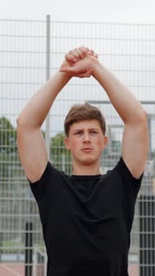 Young Man Stretching Arms Before Workout Outdoors