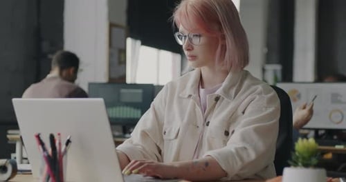 Young Woman Concentrated on Office Work Using Laptop Typing and Checking Documents