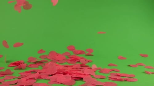 Falling heart-shaped confetti on a green background.