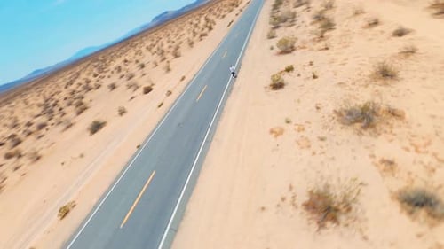 Un homme marche sur une autoroute dans le désert. Drone aérien FPV