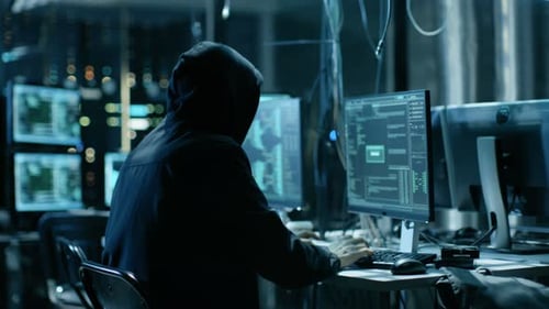 Hooded Hacker Working at Computer Station