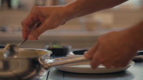 Chef puts fresh mashed potatoes in plate, close up