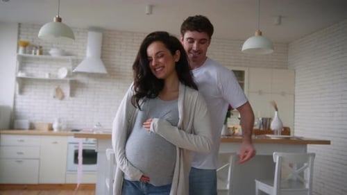 Pregnant Woman Dancing with Husband in Kitchen