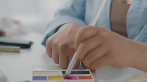Closeup View of Young Lady Hands and Bright Eyeshadow Palette in Beauty Studio Professional Makeup