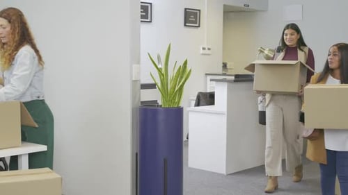 Des collègues diversifiés transportent des boîtes après la réception pour se rendre au bureau et déballent les fournitures de bureau pour l'installation