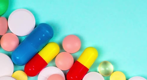 Assorted colorful pills and tablets on blue surface