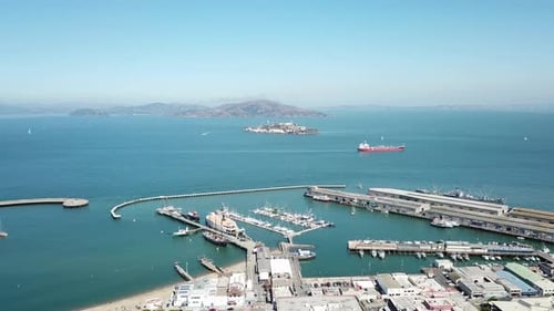 Aerial sideways of Fisherman's Wharf bay and Alcatraz island on a clear day with a boat passing. San