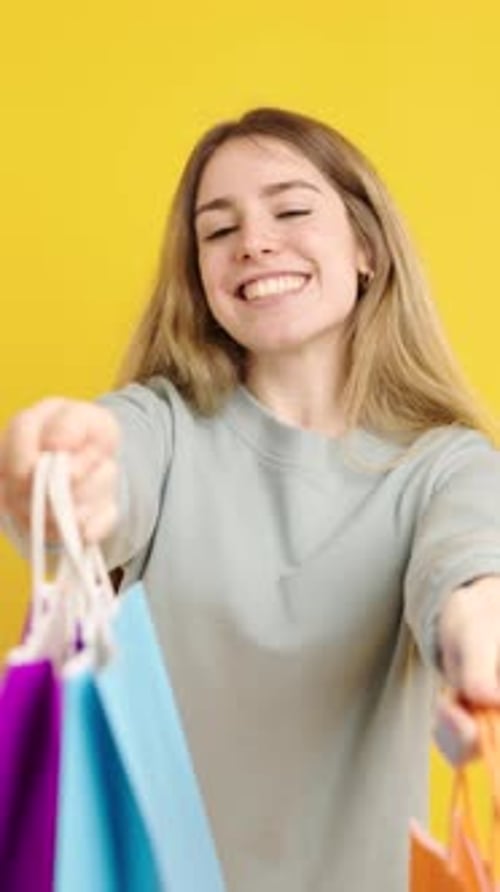 Happy Woman Holding Shopping Bags on Yellow
