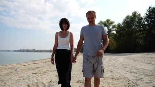 Couple Holding Hands Walking on a Sandy Beach