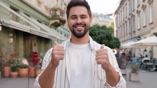 Smiling Young Adult Gives Thumbs Up on Street