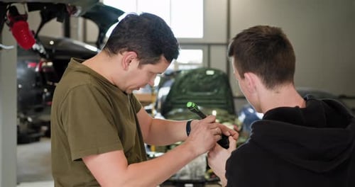 Technicians Repairing Electric Car Battery in Workshop
