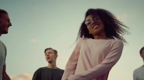Energetic Woman Dancing with Friends Outdoors in Daytime