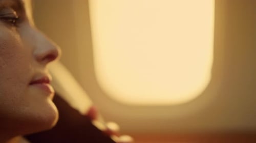Woman Talking on Phone in Airplane at Sunrise