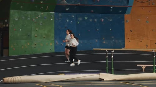 Zwei Frauen sprinten auf einer gekrümmten Indoor-Strecke Intervalltraining mit hohem Tempo, konzentrierter Beinarbeit, schnellem Tempo und