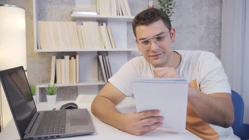 Student taking notes in notebook, thoughtful.