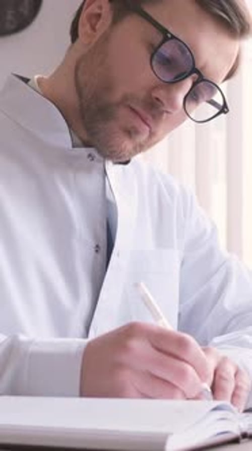 Concentrated Professional Young Doctor and Uniform is Working in His Office Doing Paperwork