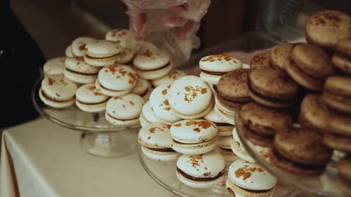 Candy Bar Macaroons Cakes a Waiter's Hand Puts a Macaron on a Plate with Macarons Slow Motion Shot