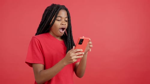 Shocked Young Person Looking at Phone on Red