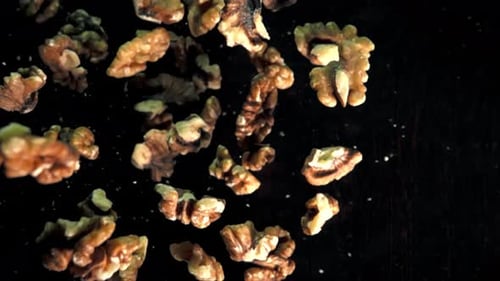 Slow Motion Walnut Pieces Falling on a Dark Background in a Studio Setting