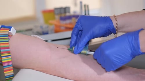 Closeup of a Female Doctor Injecting a Patient with a Syringe for Blood Sampling