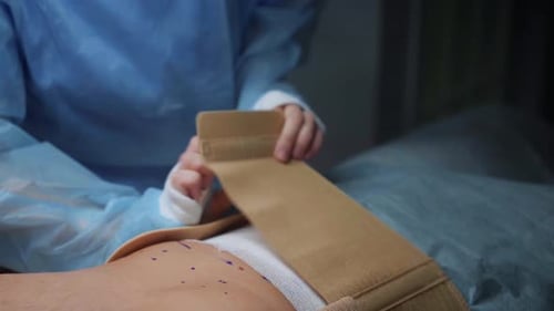 Surgeon Applies Corset on Patient After Procedure in Medical Facility