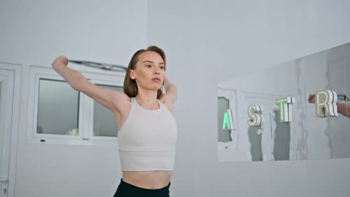 Focused fitness model arm workout with elastic strap at home studio