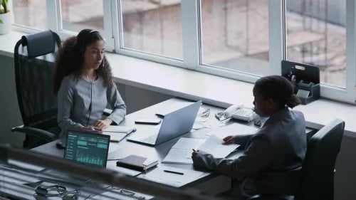 Zwei interkulturelle Geschäftsfrauen diskutieren über Momente der Arbeitsorganisation