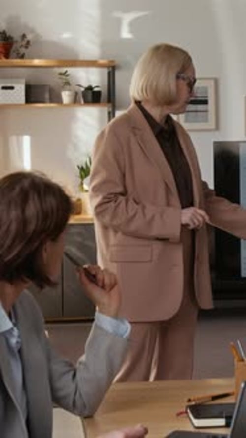 Woman Showcasing Data and Graphs on Monitor to Two Attendees in Office