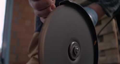 Worker’s hand gripping electric grinder, cutting metal with focus and control, sparks flying
