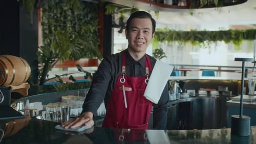 Asian Bar Worker in Apron behind Counter