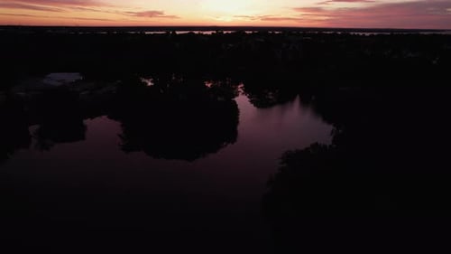 Beautiful tilting aerial view of an orange sunset over lakes and forests