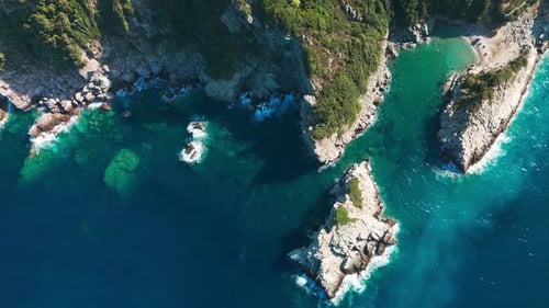 A stunning coastline with turquoise waters and rocky cliffs on a sunny day, aerial view