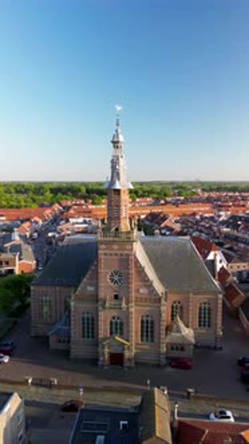 Aerial view of a European town with a central red-brick church and steeple, surrounded by houses
