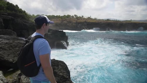 Man Looking at Waves Crashing and White Water at edge of Rock - Not Safe to Swim