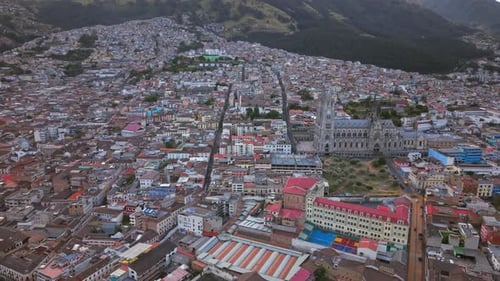 Side drone pan over Quito city and basilica skyline