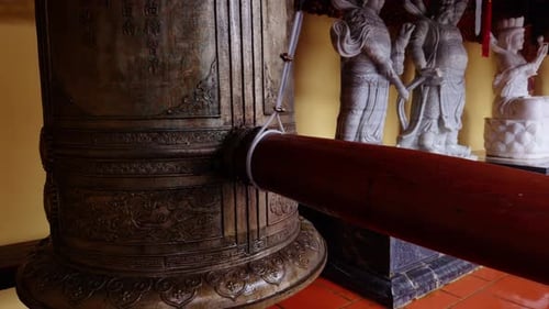 Large Ornate Bronze Bell With Wooden Striker Positioned to Hit Its Center Surrounded by White